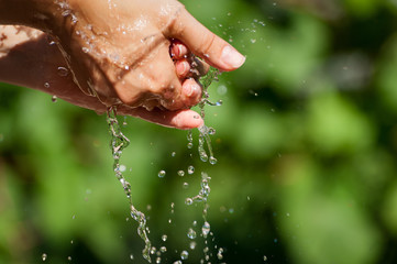 Fototapeta premium Woman washing hand outdoors. Natural drinking water in the palm. Young hands with water splash, selective focus