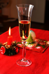 Glass of champagne, candle and delicious dessert in form of christmas tree ball on the tablr in new year's eve