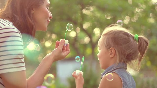 Beautiful mother and her little daughter having fun in summer park together. Slow motion 4K UHD video 3840X2160