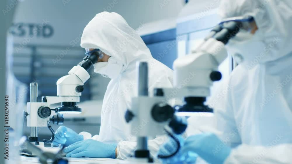 Aufkleber two engineers/ scientists/ technicians in sterile cleanroom suits use microscopes for component adju