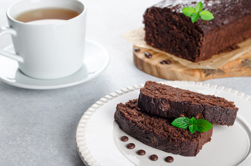 Two slices of chocolate cake with mint leaves served on a white