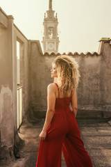 Beautiful and elegant woman back portrait standing on rooftop while wearing red dress