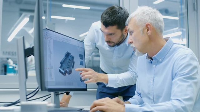 Industrial Designer Has Conversation with Senior Engineer While Working in CAD Program, Designing New Component. He Works on Personal Computer with Two Monitors. 