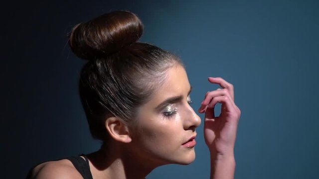 Brunette teenager in brilliant make-up dances and looks at camera