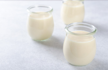 Lemon or vanilla curd in glass jars on a light stone table, sele