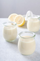 Obraz na płótnie Canvas Lemon or vanilla curd in glass jars on a light stone table, sele