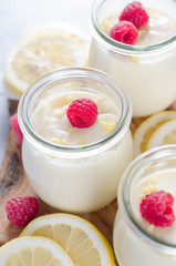 Lemon or vanilla curd in glass jars with raspberry and lemon sli