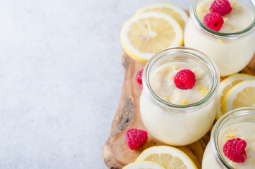 Lemon or vanilla curd in glass jars with raspberry and lemon sli