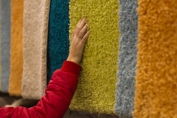 Woman spends shopping and selects plush carpets by hand in the store