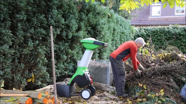 Herbst-Arbeitsplatz im Garten mit H&auml;cksler und Komposthaufen