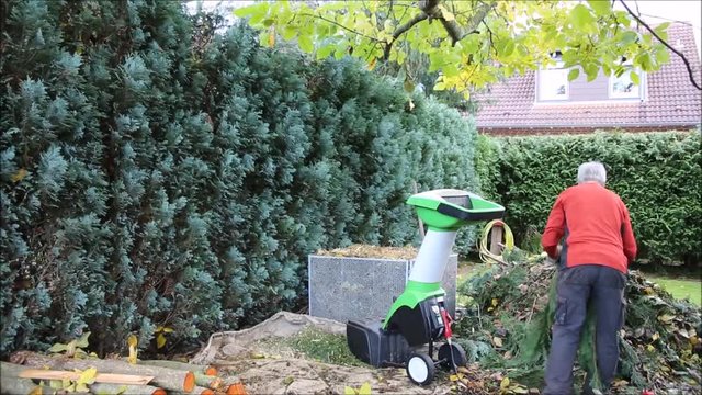 Herbst-Arbeitsplatz im Garten mit H&auml;cksler und Komposthaufen