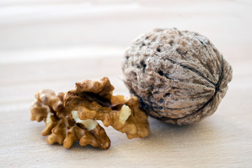Walnut kernels and whole walnuts on rustic old wooden table