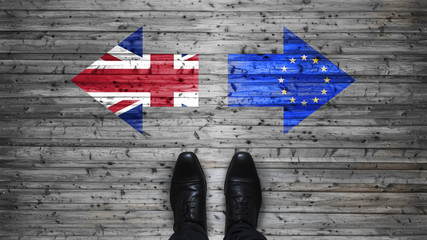 Brexit, flags of the United Kingdom and the European Union on wooden background with legs and shoes