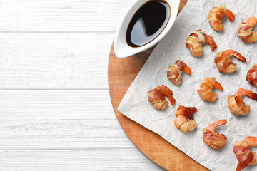 Board with shrimps wrapped in bacon on table