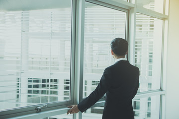 Fototapeta premium Portrait Asian businessman in black suit on the building from back angle,thailand people