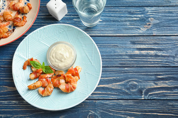 Plate with shrimps wrapped in bacon and sauce on table