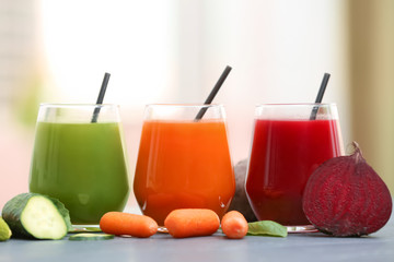 Glasses with various fresh juices and ingredients on table