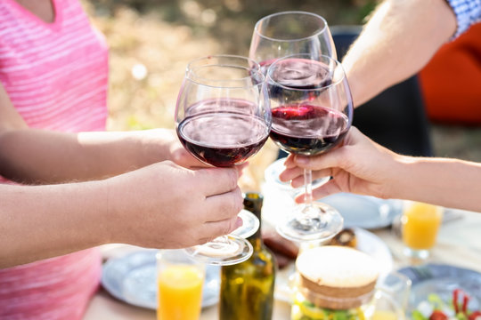 Happy family with glasses of wine having barbecue party outdoors