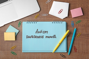 Words "Autism awareness day" written in notebook on wooden table