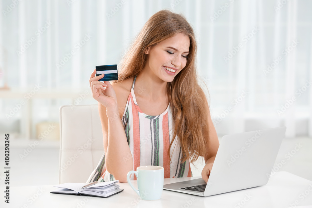 Canvas Prints Young woman using laptop while holding credit card at home. Internet shopping concept