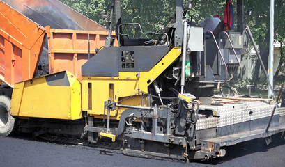 Road construction. Applying new hot asphalt using road construction machinery and power industrial tools. Roadworks repaving process.