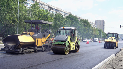 Road construction. Applying new hot asphalt using road construction machinery and power industrial tools. Roadworks repaving process.