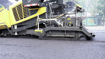 Road construction. Applying new hot asphalt using road construction machinery and power industrial tools. Roadworks repaving process.