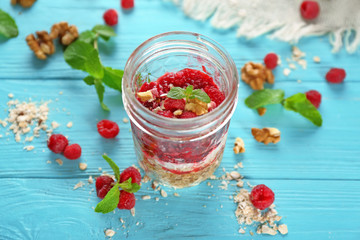 Delicious parfait with raspberry and oatmeal in glass jar on table