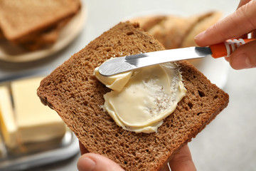 Woman spreading butter on slice of bread, closeup