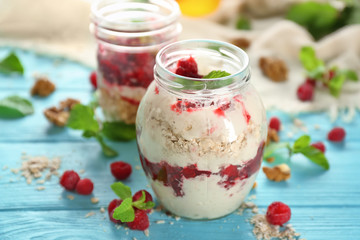 Delicious parfait with raspberry and oatmeal in glass jar on table