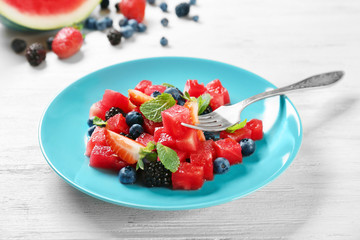 Plate with delicious watermelon salad on wooden table