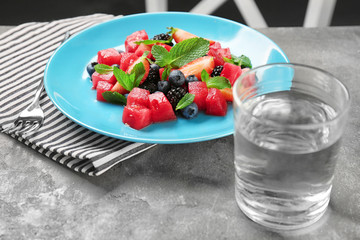 Plate with delicious watermelon salad and glass of water on table
