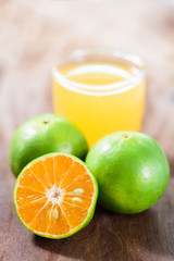 Green tangerine orange fruit and juice on wooden background, healthy food