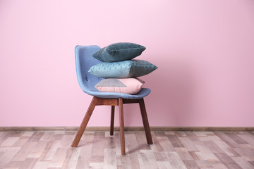Stack of pillows on chair near color wall