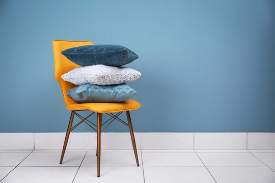 Stack of pillows on chair near color wall