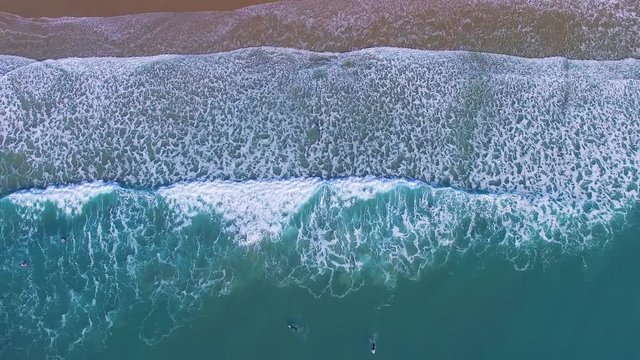 Aerial view of surfers in an amazing and unspoiled beach 