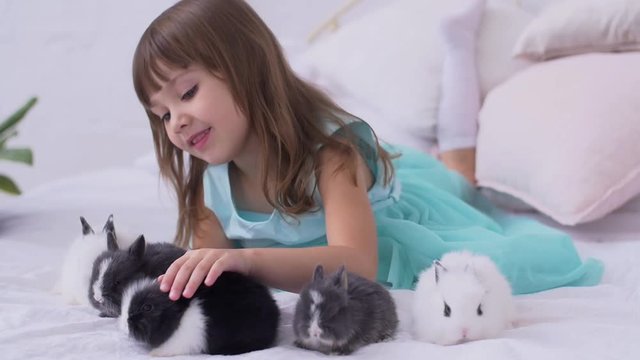 Pretty teen girl having fun, hugging and playing with decorative rabbit