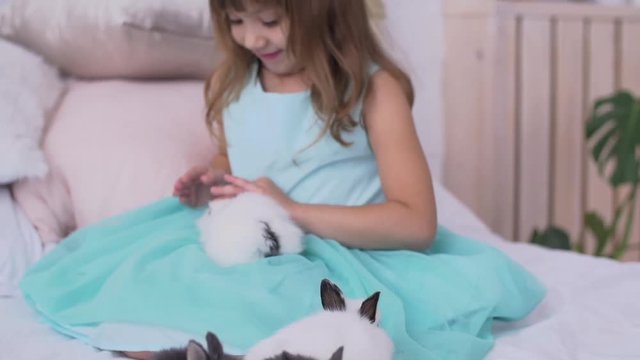Pretty teen girl having fun, hugging and playing with decorative rabbit