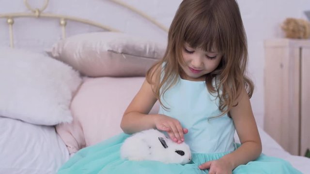 Pretty teen girl having fun, hugging and playing with decorative rabbit