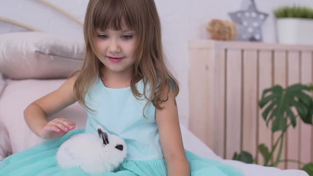 Pretty teen girl having fun, hugging and playing with decorative rabbit