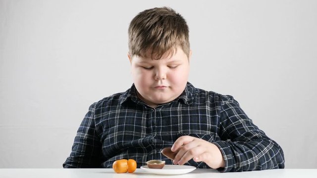 Young fat boy eats a chocolate egg 50 fps