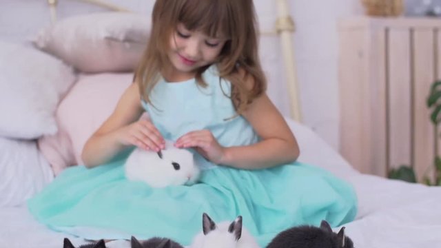 Pretty teen girl having fun, hugging and playing with decorative rabbit