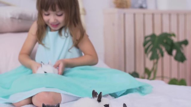 Pretty teen girl having fun, hugging and playing with decorative rabbit