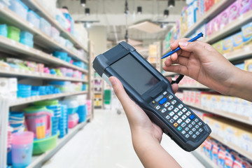 Asian hands holder handheld with supermarket background,check stock,worker use for keep data of products,Connect database online with wifi