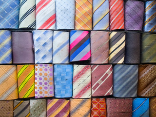 Fototapeta premium Close up of rolled up neckties. Shot of a multi-colored collection of rolled-up ties. Colorful ties rolled up and placed in rows. 