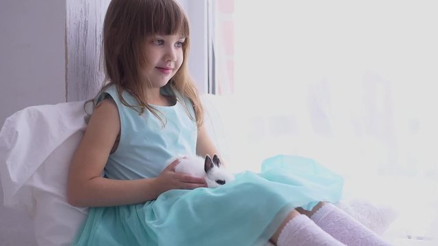 Pretty teen girl having fun, hugging and playing with decorative rabbit