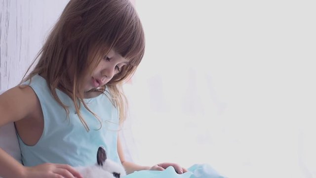 Pretty teen girl having fun, hugging and playing with decorative rabbit