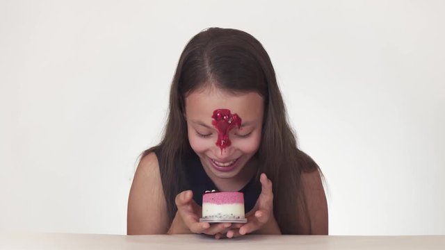 Beautiful naughty teenage girl joyfully smears cake face on white background stock footage video