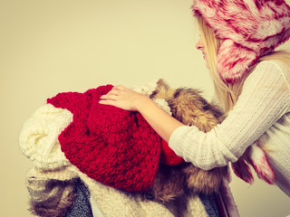 Woman in winter hat holding pile of clothes