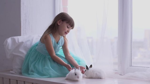 Pretty teen girl having fun, hugging and playing with decorative rabbit